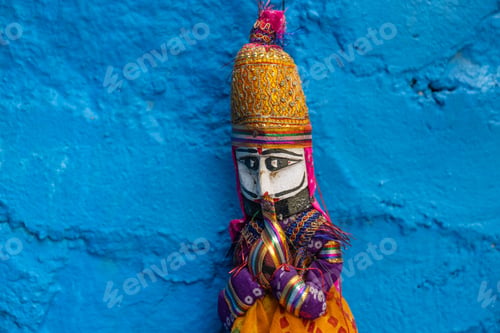 Preview: Closeup of a colorful Rajasthani puppet hanging on a blue wall