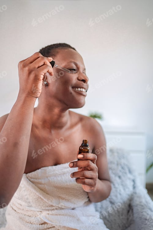 Preview: Young woman applying essential oil on her face