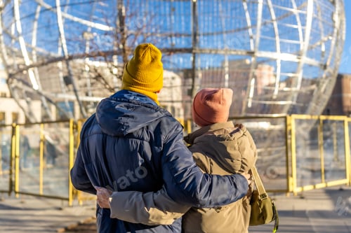 Preview: Senior couple embracing and admiring christmas decorations in winter city
