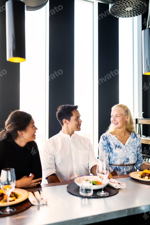 Preview: Happy young friends having conversation in restaurant