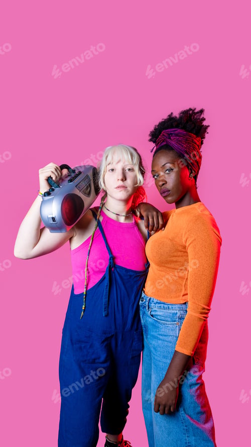 Preview: Two young diverse women holding boombox posing confident isolated advertising copyspace