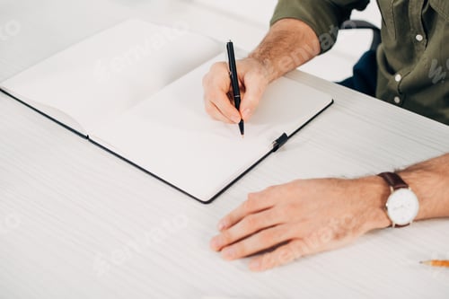 Preview: Cropped view of man writing with pen in notebook