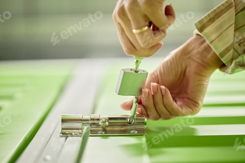 Preview: Hands of Woman Locking Door with Padlock Using Key Closeup