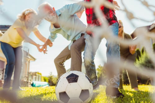 Preview: Senior people playing football in the backyard