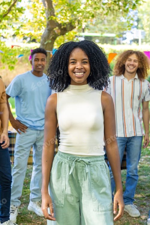 Preview: Young woman smiling with friends at a party in the park