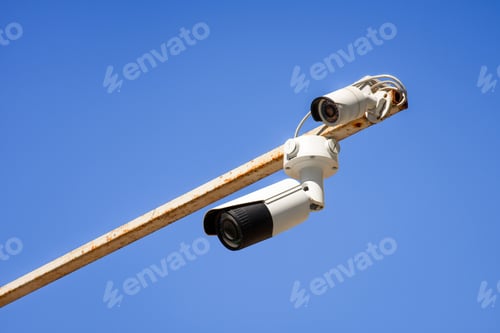 Preview: close up view of security cameras on pole against bright blue sky
