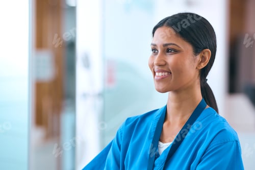 Preview: Head And Shoulders Portrait Of Smiling Female Doctor Or Nurse Wearing Scrubs In Hospital