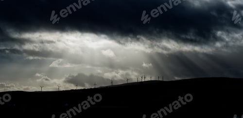 Preview: Landscape with wind turbines and dark clouds looming in the sky above them in Ireland
