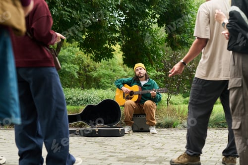 Preview: Young Adult Caucasian Man Playing Acoustic Guitar Outdoors Entertaining Crowd