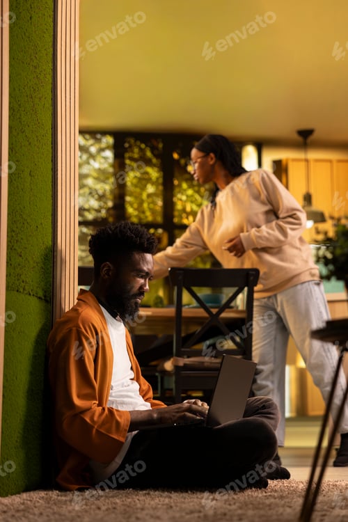 Preview: African American person, browsing on laptop, cozy moment, on floor hallway