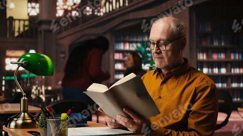 Preview: Old person with spectacles enjoys reading a book at the library