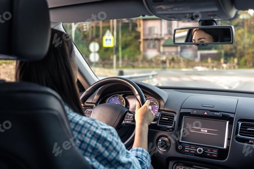 Preview: Woman driving a car, hands on the wheel close-up, view from the back to the road.