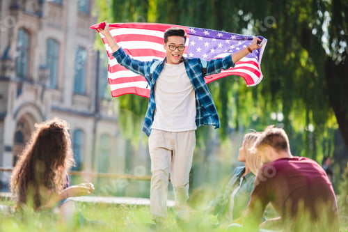 Preview: multicultural students with american flag in summer park