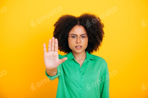 Preview: Dissatisfied frustrated brazilian or hispanic curly haired woman, shows stop gesture with palm of