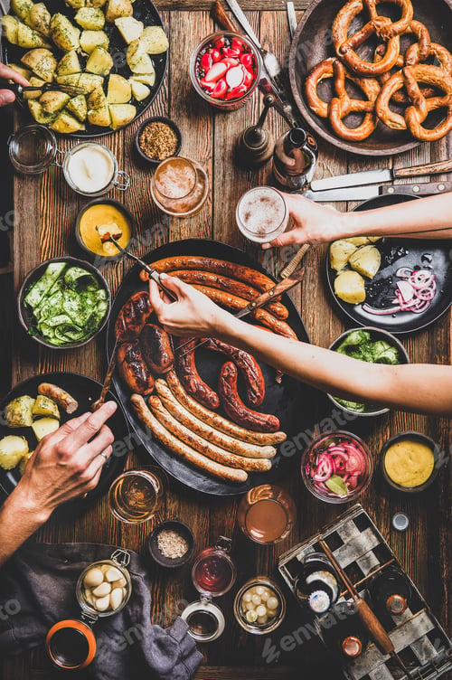 Preview: Octoberfest dinner table with beers, sausages, peoples hands with snacks