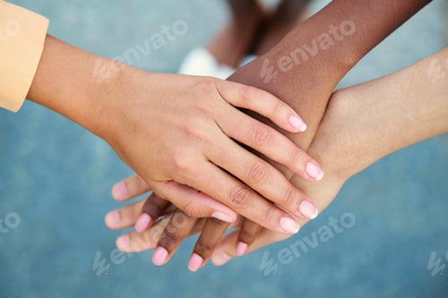 Preview: Top view of young multiracial people putting their hands together.