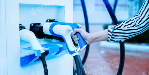 Visualização: Conectando manualmente um carregador na tomada de um carro elétrico. O carro elétrico ou EV está carregando na estação.