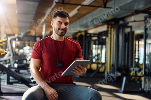 Preview: Happy coach using digital tablet in a gym and looking at camera.
