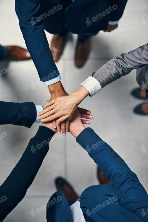 Preview: High angle shot of a group of businesspeople joining their hands together in unity