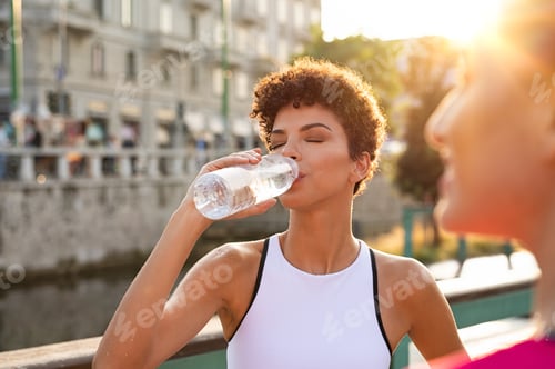 Preview: Athletic woman drinking water after workout
