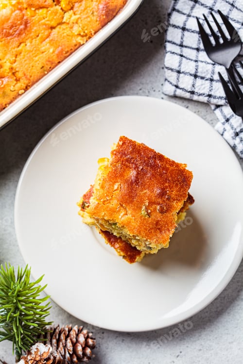Preview: Portion of Christmas cheddar cornbread on white plate. Festive recipe food concept.