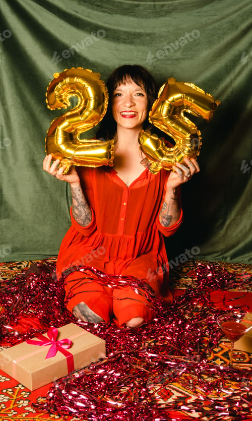 Preview: Young beautiful woman with piercings and tattoos holds balloons in the form of numbers 25