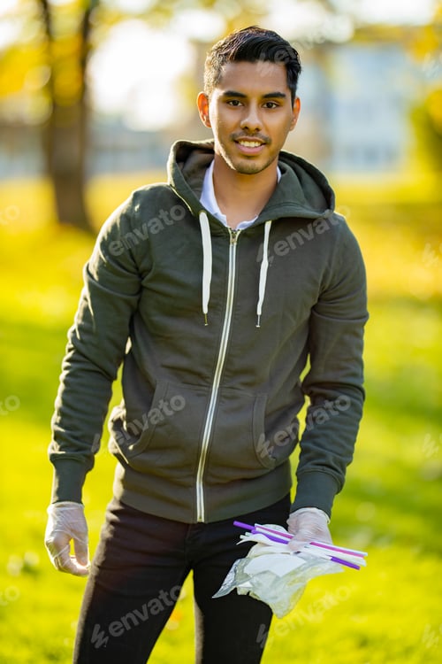Preview: Back lit portrait of man cleaning garbage on sand at park