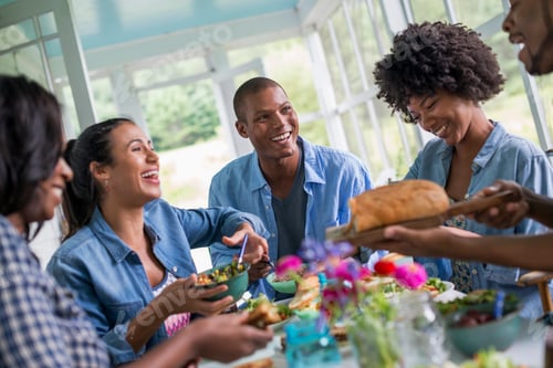 Preview: A group of women and men around a table sharing a meal in a farmhouse kitchen.