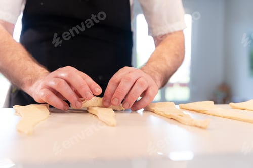 Preview: Hands of a man cooking croissants, shaping with the puff pastry, work at home