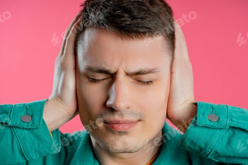 Preview: Annoyed man with shut ears on pink background. Guy block annoying sounds