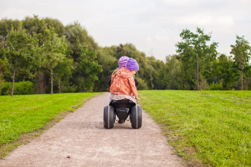 Preview: Back view of adorable little girls ride a motorbike outdoor