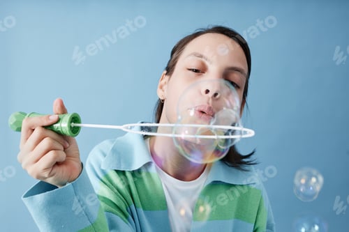 Preview: Girl with disability blowing bubbles against blue