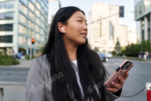 Preview: Business Chinese woman wearing earphones and calling on the street