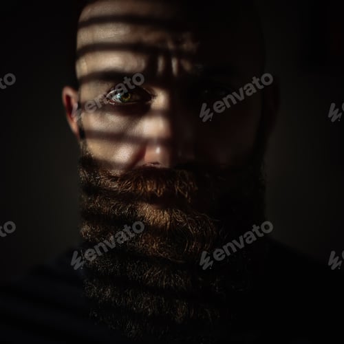 Preview: Close-up portrait of middle aged brutal bearded man with expressive eyes and striped shadows on face
