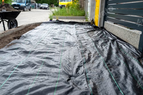 Preview: The plowed garden in front of the fence in the house, covered with black agrofiber