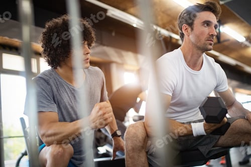 Preview: Young fit man doing workout with a personal trainer