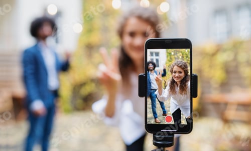 Preview: Young couple making video with smartphone outdoors on street, tik tok concept.