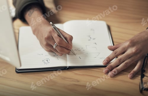 Preview: Shot of an unrecognisable businessman writing in a notebook during a late night at work