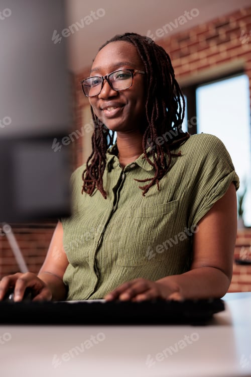 Preview: Portrait of smiling african american programmer working remote from home looking at computer screen