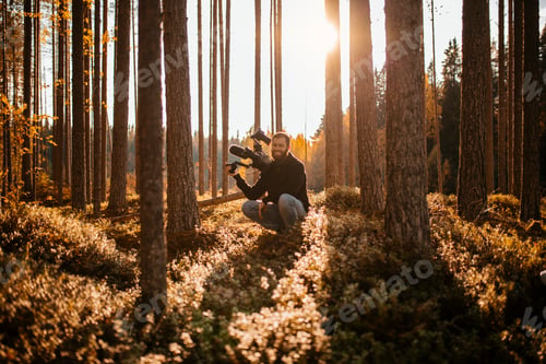 Preview: Man crouching in forest holding camcorder