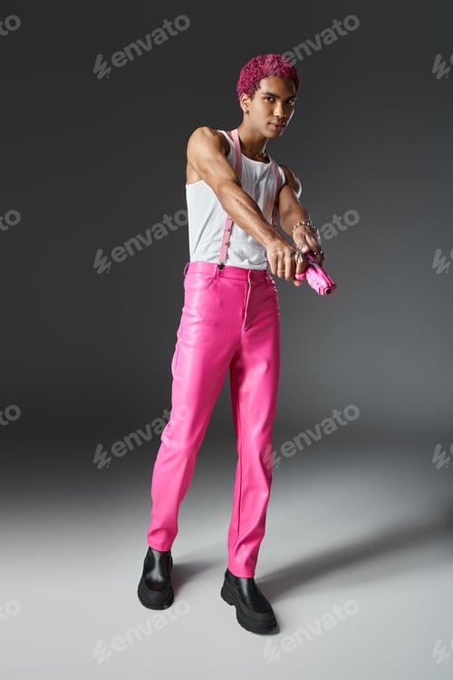 Preview: fashionable man with pink curly hair wearing pants with suspenders and holding pink toy gun