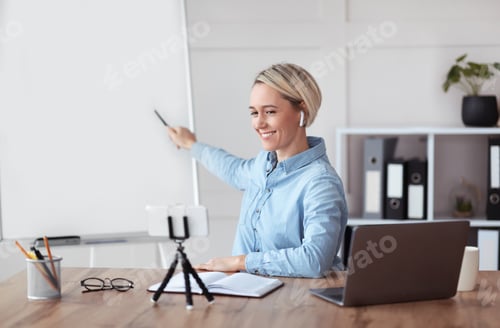 Preview: Joyful young teacher giving online private lesson from home, pointing at empty blackboard with space