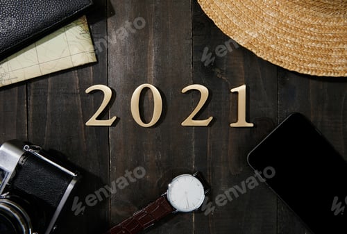 Preview: Camera, watch, smartphone, wallet, map and 2021 made with plastic numbers on a wooden table