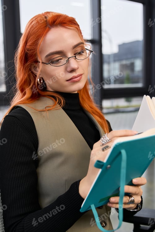 Preview: Young woman with red hair engaged in creative work in a modern office setting