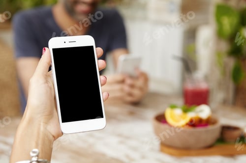 Preview: Woman holding cell phone for reading or sending message, surfing internet during breakfast at restau