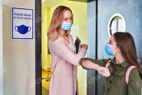 Preview: Teacher and schoolgirl having an elbow greeting during pandemic