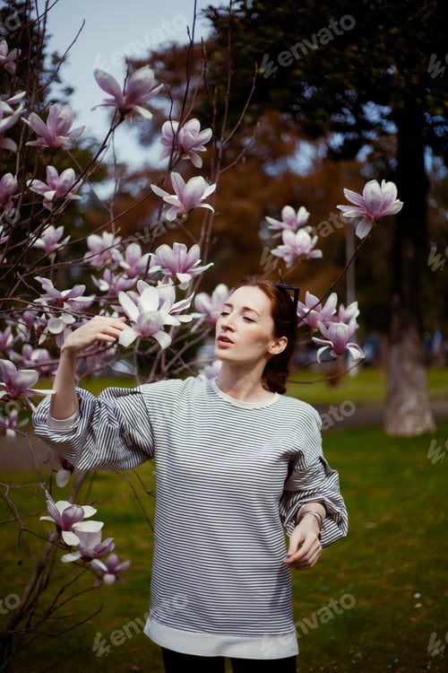 Preview: Woman admiring pink and white flowers in park
