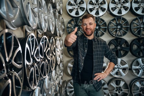 Preview: Thumb up, gesture. Man worker is maintenance station with tires, wheels