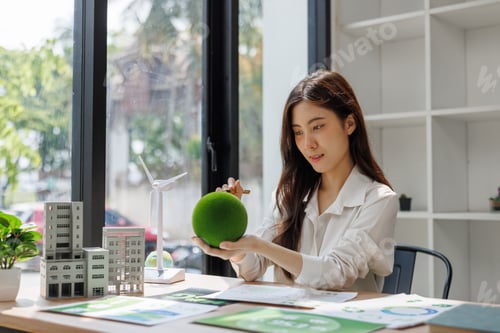 Preview: Woman holding green sphere planning sustainable urban development