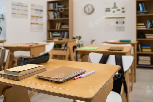 Preview: Empty Classroom Showing Student Desks with Notebooks and Stationery Items